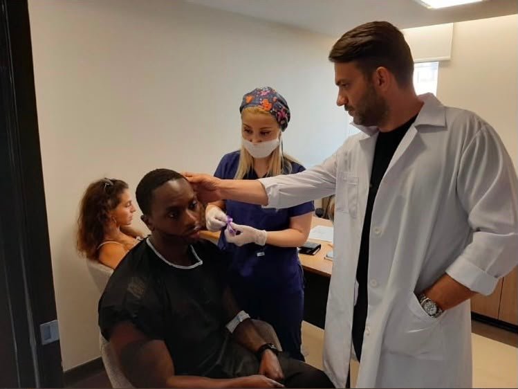 A patient surrounded by people in clinical clothing, photograph supplied by Clinique World