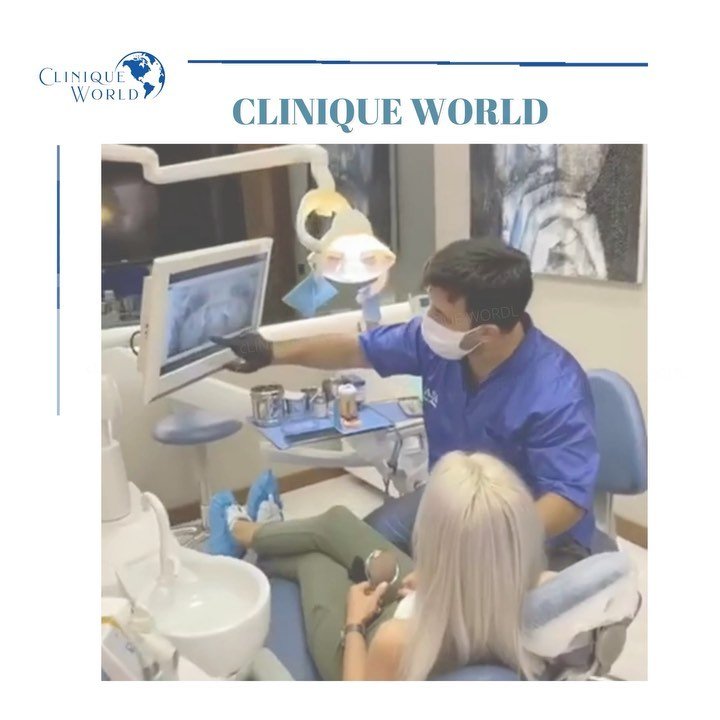 A professional shows a female patient a dental examination on a screen